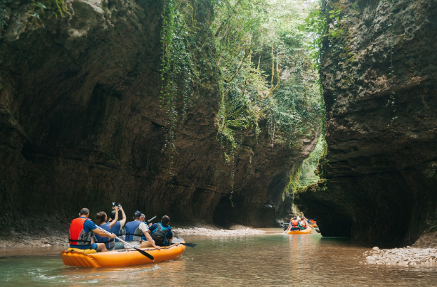A few rafts floating in a calm river with towering cliffs on either side