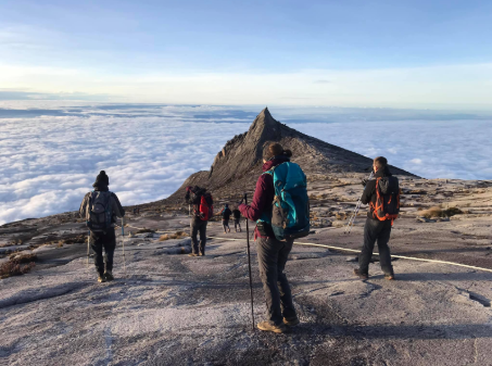 A few hikers reaching the tip of Mount Kinabalu on a sunny day
