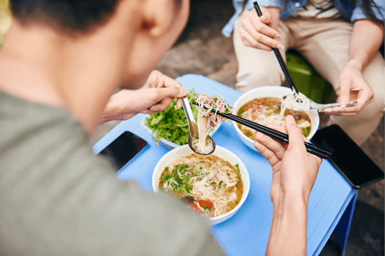 two tourist enjoying bowl of pho