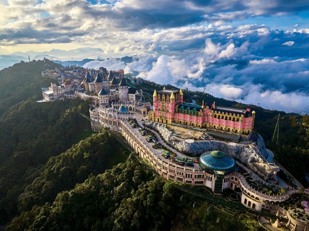 Aerial view of Ba Na Hills theme park perched above the clouds in Da Nang, Vietnam, featuring a colorful European-style castle and village