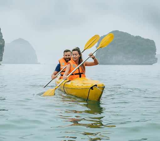 couple rowing kayak at foggy sea in ha long bay