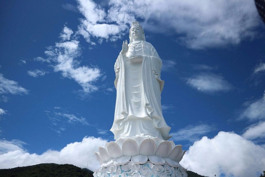 Towering white Lady Buddha statue at Linh Ung Pagoda, Son Tra, Da Nang, standing on a lotus pedestal against a bright blue sky