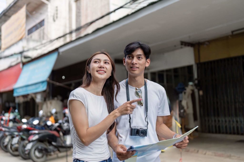 Couple with a camera and map exploring a local street, reflecting Vietnamese etiquette tips for travelers navigating unfamiliar neighborhoods